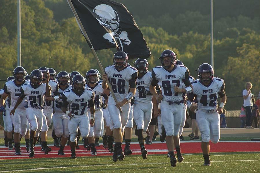 Senior Blaine Hedlund leads the team with the flag in the season opener on Sept. 4 at Lansing. Each game, the seniors choose who carries the flag.