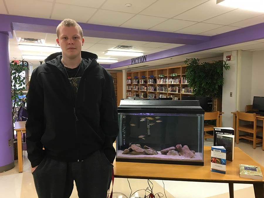 Schuley poses with the 35-gallon tank, which is a much smaller version of what he plans to use for his completed senior project.