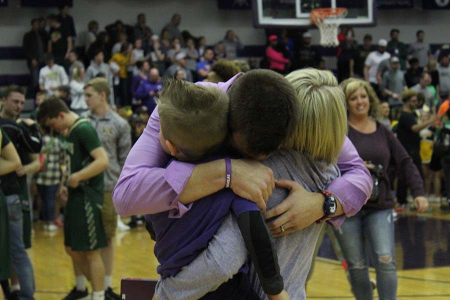 Overwhelmed with emotion, head coach Bryan Shelley embraces his wife and son. The first-year coach and his team earned a spot in the state tournament with their 54-52 win over rival Basehor.