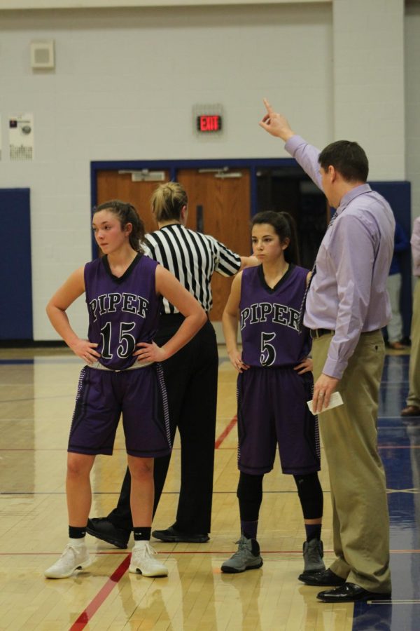 Sophomore Grace Banes and junior Brianna Andrade get their game plan from coach Shane Stout for the next play.