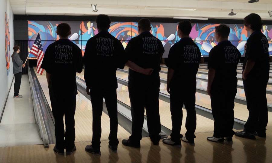 Before the bowling starts, the teams are announced and line the lanes. The boys turn around for the national anthem.