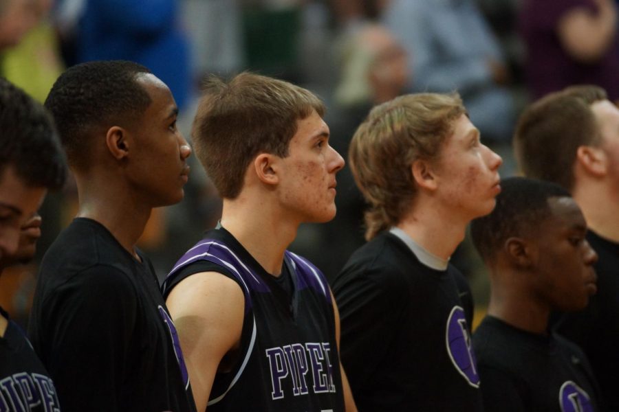 Senior Bryce Yoder, freshman Tamar Bates and sophomore Brendyn Bard stand for the national anthem March 3.