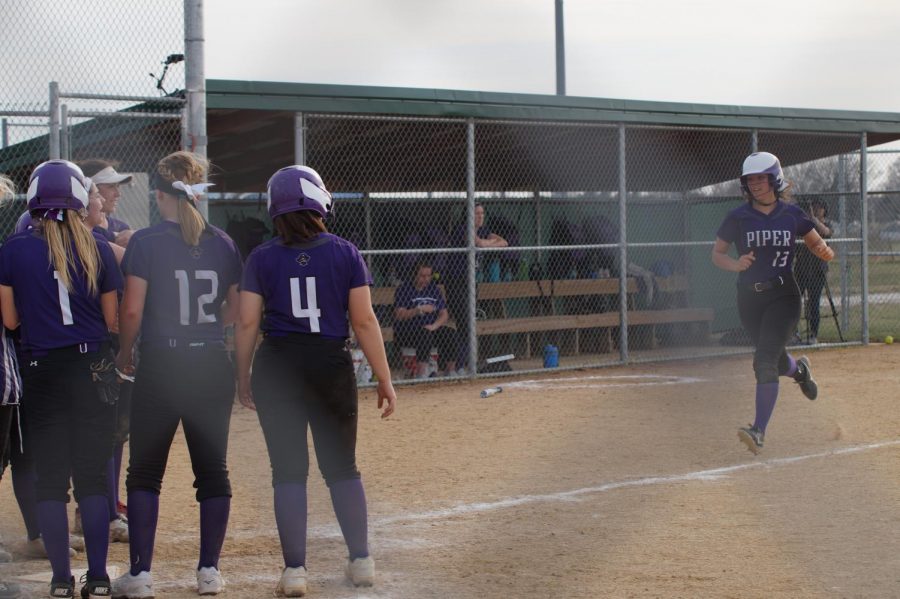 Alexis Rymer greets her team at homeplate after rounds the bases after hitting a home run April 11.
