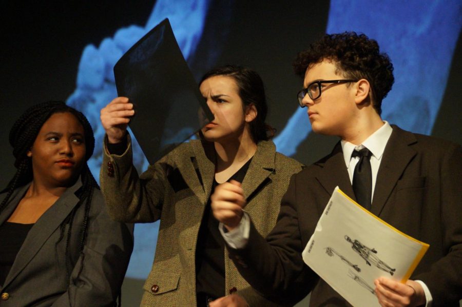 Freshman Amaya Starks, Junior Ally Viera, and Sophmore Trent Smith examine the x-rays as they play corporate managers during the spring production of Radium Girls, April 26.