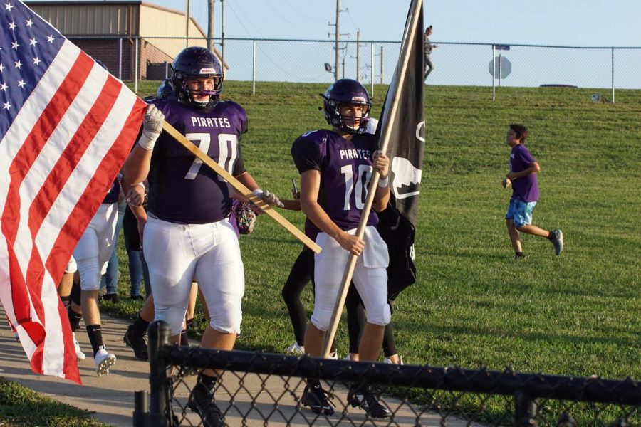 Seniors Dalton White and Cooper Beebe lead the team to the field while carrying the Pirate and US flag. 