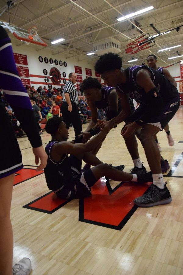 Senior Trey Bates is helped up by his teammates after being fouled.