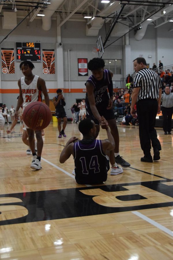 Senior Brandon Jackson helps sophomore teammate Tamar Bates after he was fouled. 