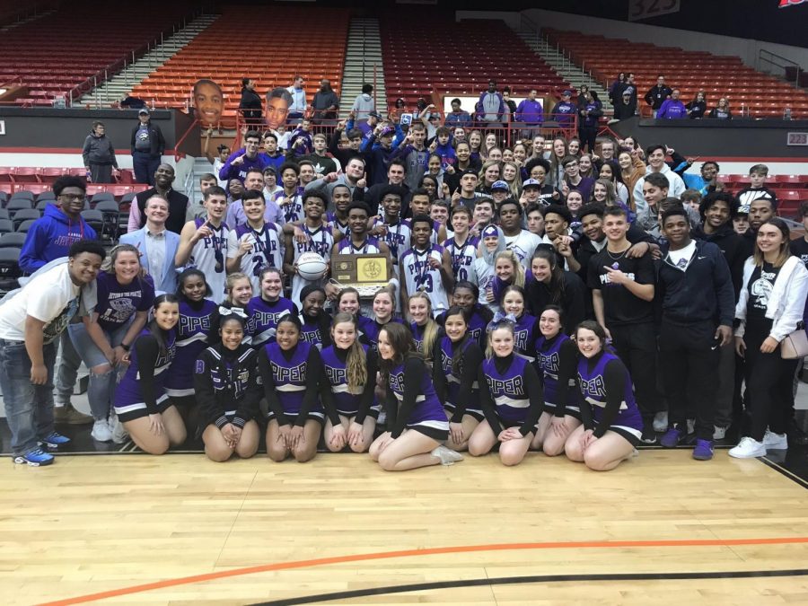 The boys basketball team poses with their first place trophy with fans and cheerleaders after defeating Augusta.