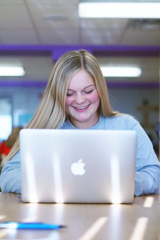 Junior Kaitlyn Bradbury uses her personal Apple Macbook in the school library.