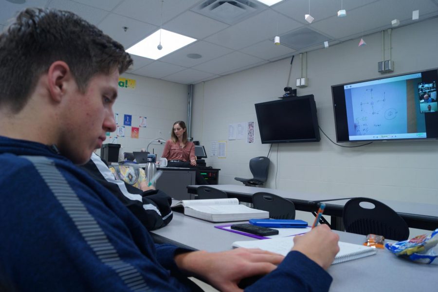 Junior Blake Beashore takes notes in AP physics while teacher Josh Cochran explains the lesson over Skype. 