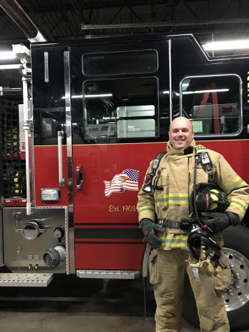 Social sciences teacher Matthew Reitemeier stands in front of a fire truck while in full uniform.