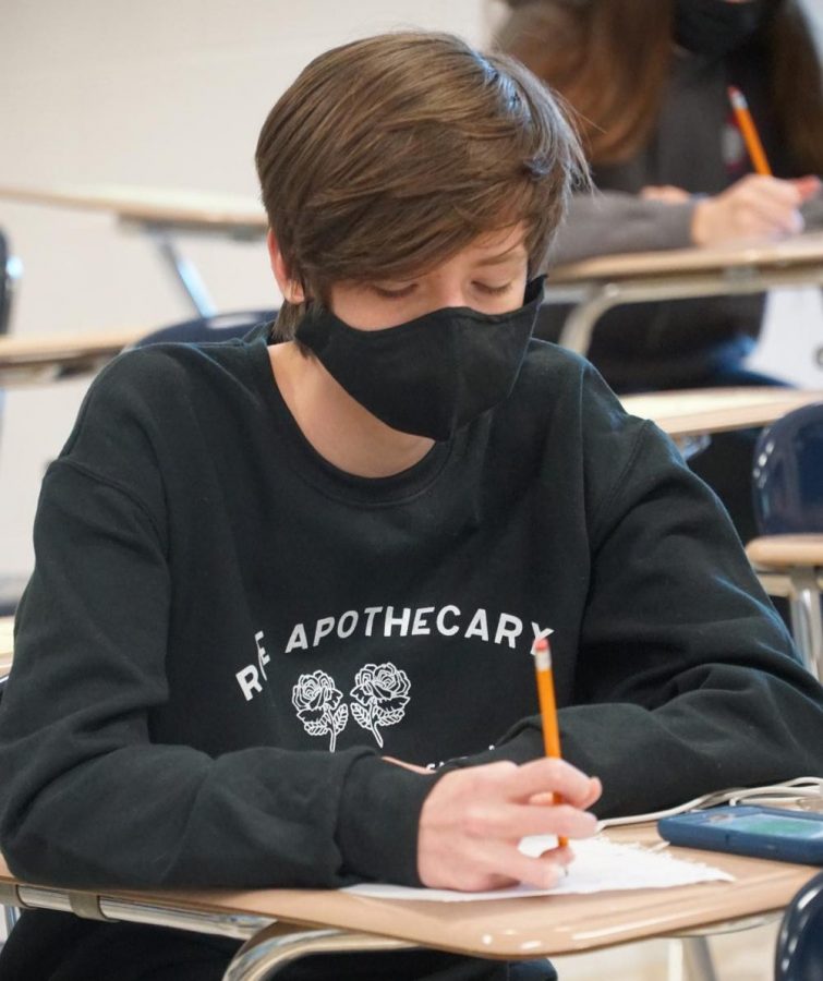 Freshman Jack Wells writes on a piece of paper during a Scholars Bowl meet.
