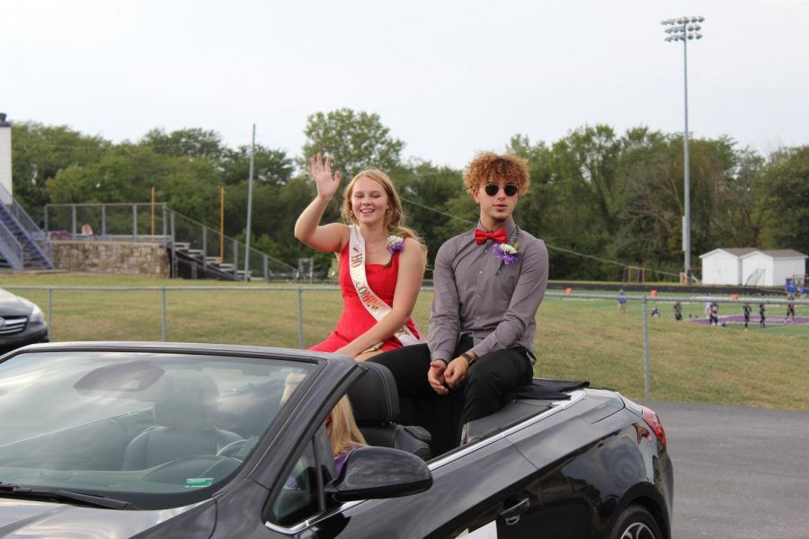 Homecoming candidates Zoey Pudenz and Alex Ivanuska wave while riding in the back of a convertible.